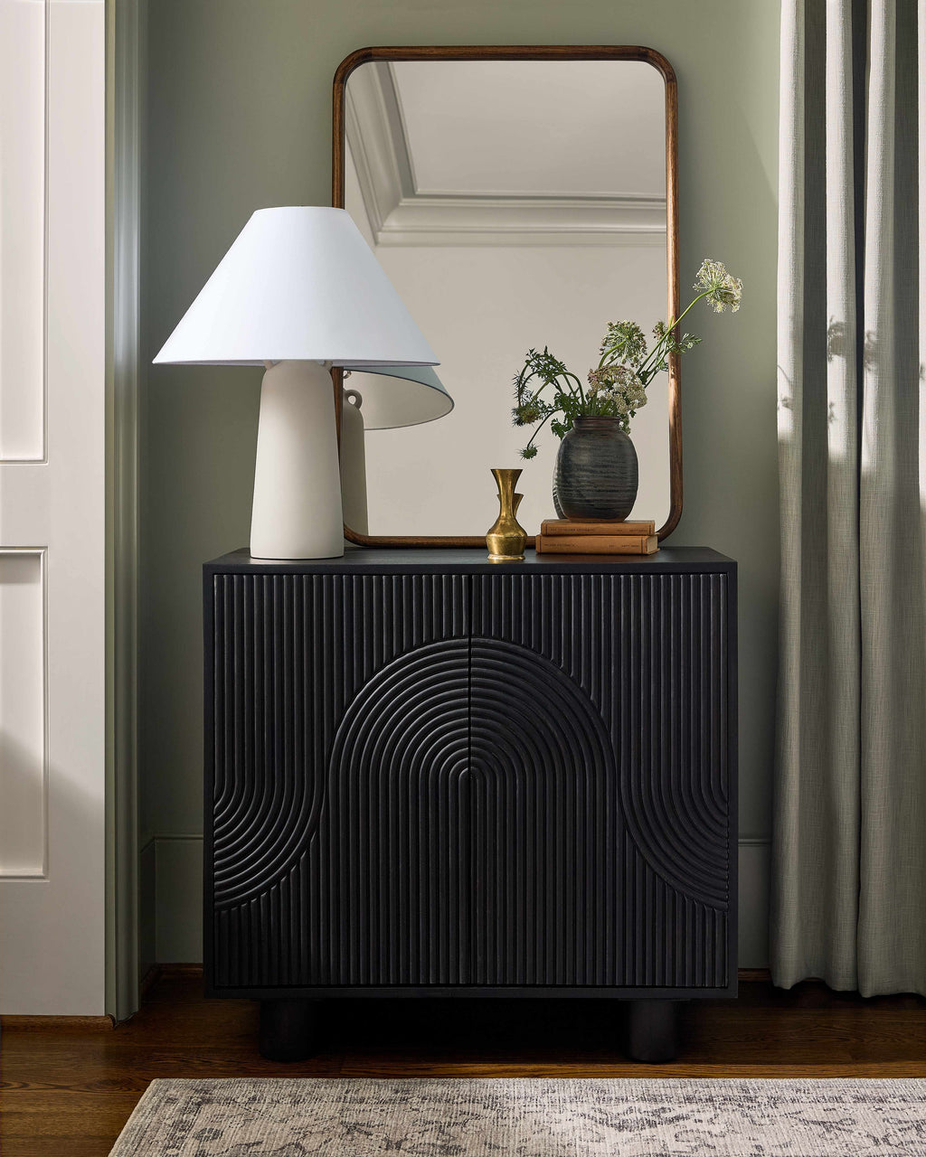 Contemporary Black Storage Cabinet with Natural Wood Detailing with a lamp, mirror, and decorative items in a room.