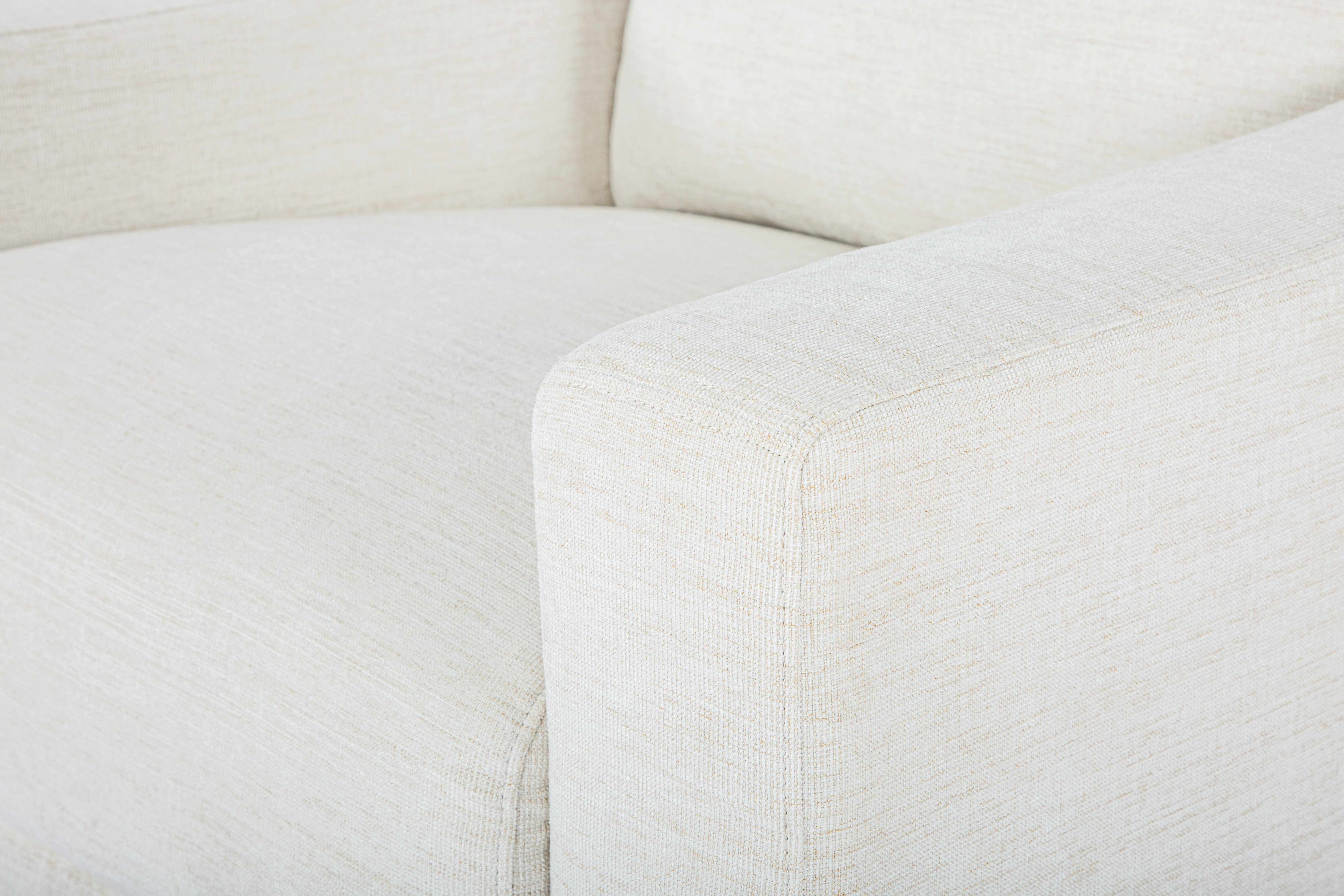 Close-up of a white sofa with visible texture, Contemporary Scandinavian-style chair, sleek minimalist seating, armchair in a room, beige accent chair with a pillow
