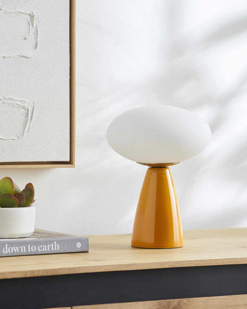 Contemporary Table lamp with white shade and mustard yellow base on a wooden surface