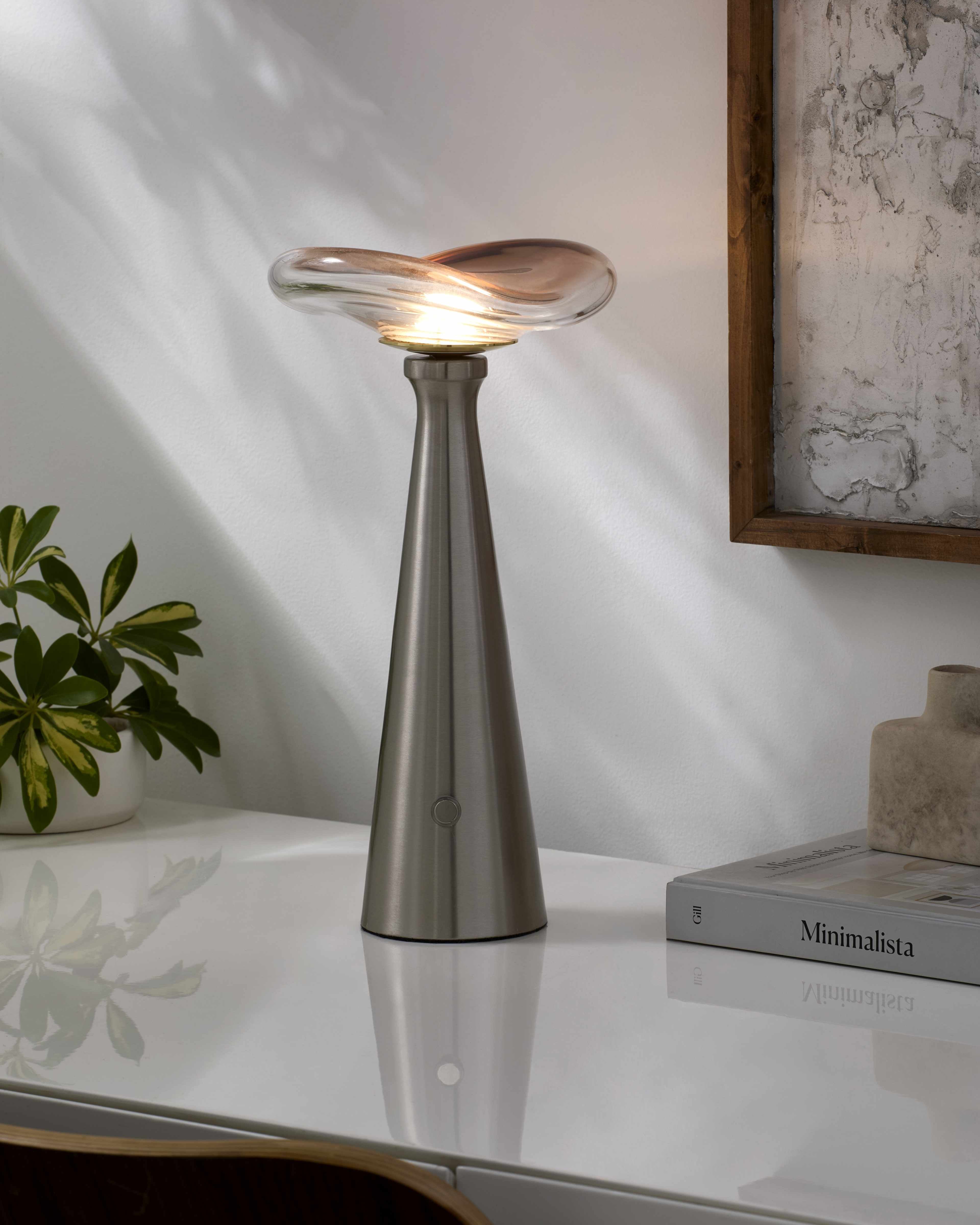 Contemporary table lamp with smoky charcoal glass shade on a table in a modern living room when turned on
