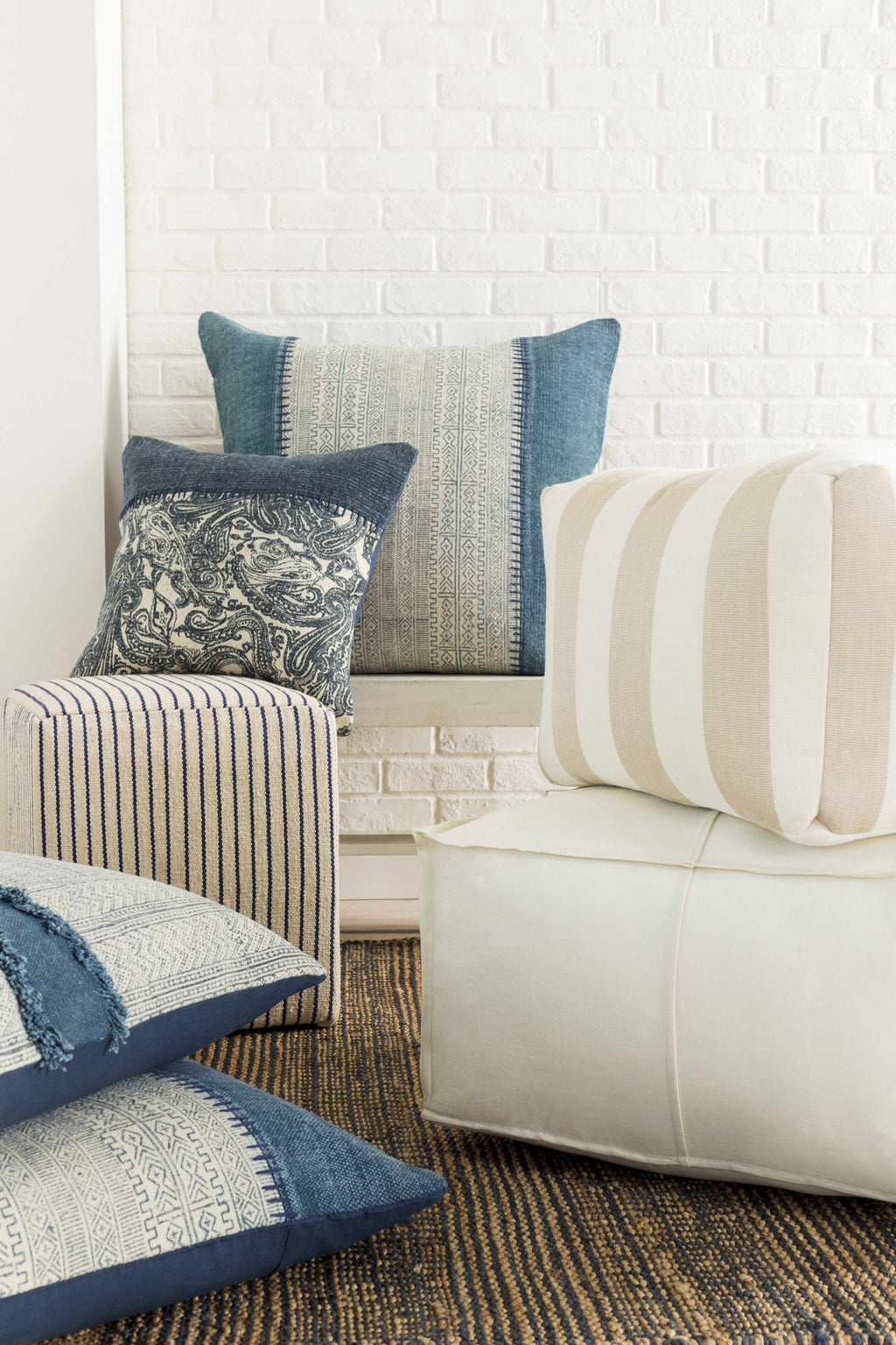 Decorative pillows on a sofa against a white brick wall.