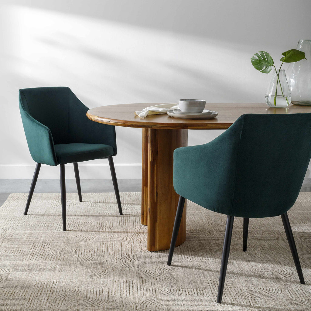 Dining table with two green chairs and a small plant on a neutral background