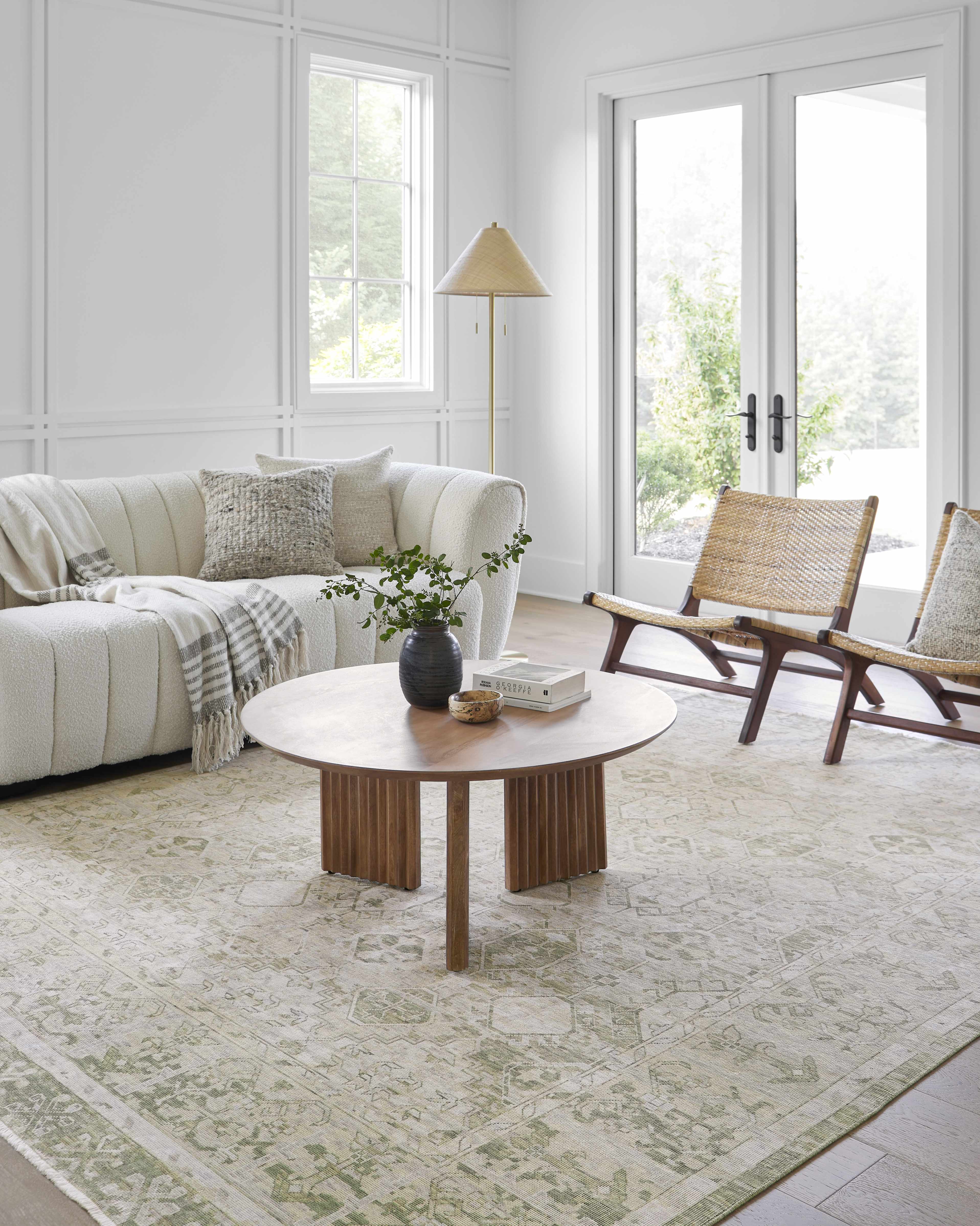 Living room with a white sofa, wooden coffee table, and wicker chairs.