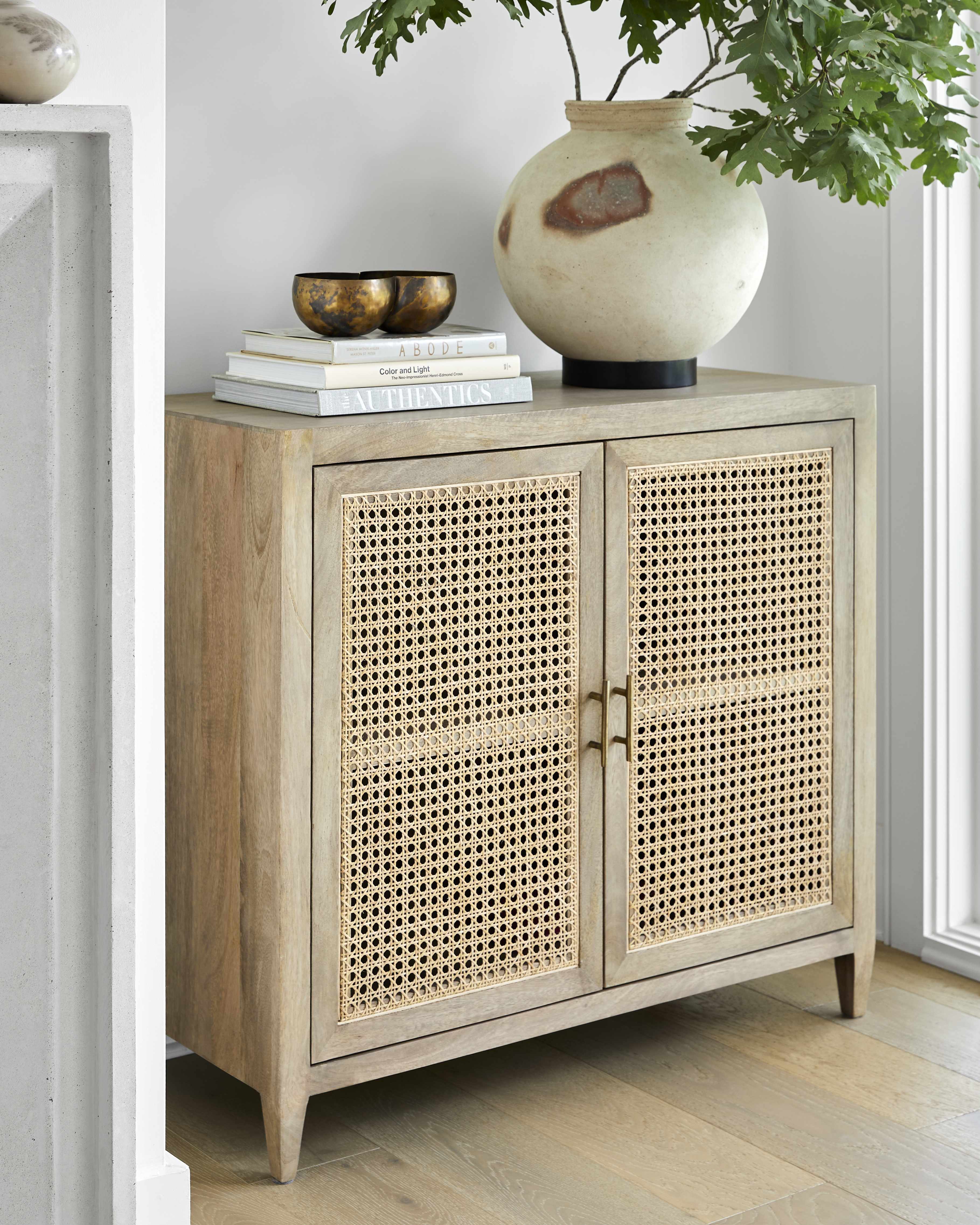 Mango wood modern cabinet with rattan doors in a room with a vase and books on top