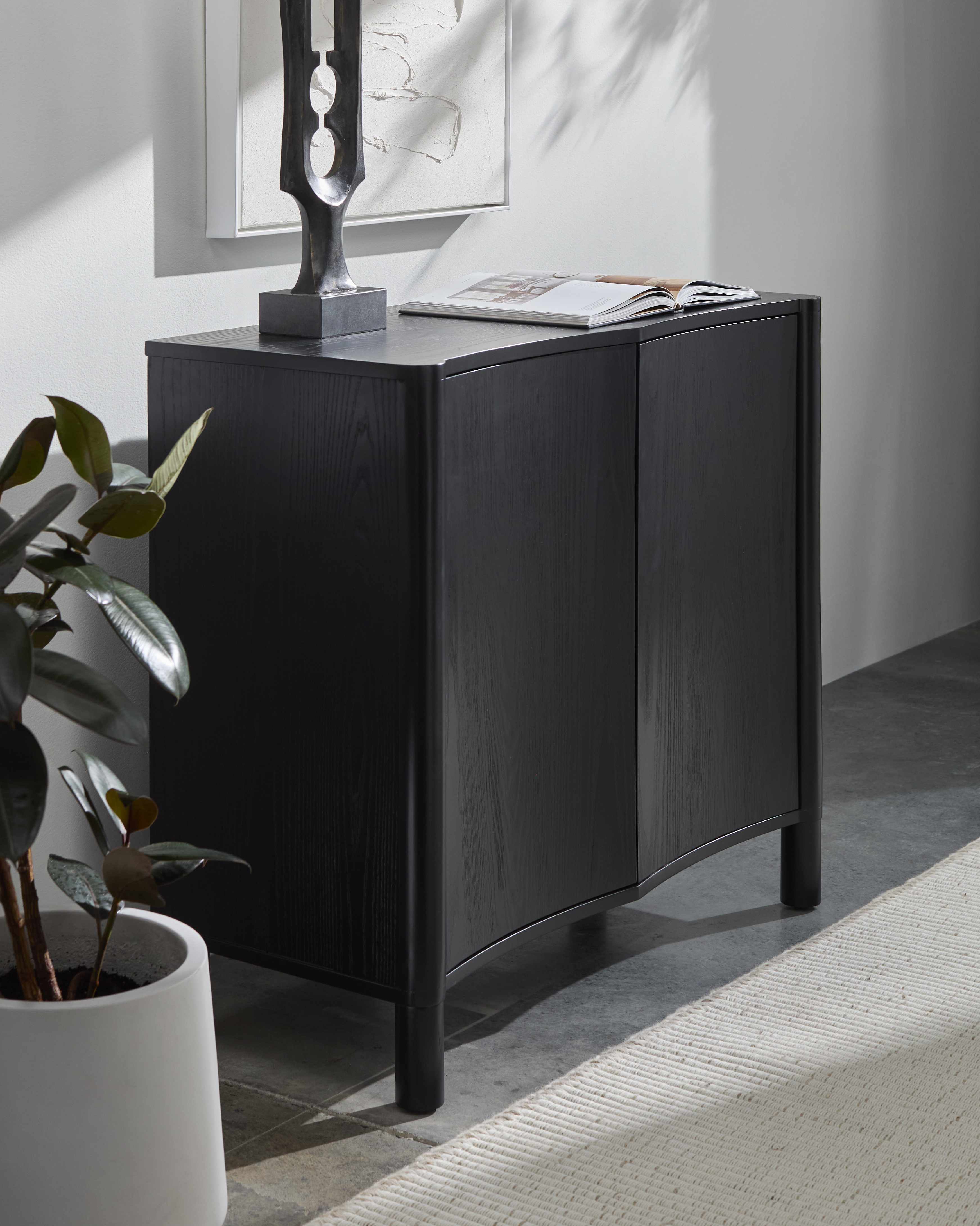 Modern black wood cabinet with minimalist Scandinavian design in a room with flower and ornament decoration
